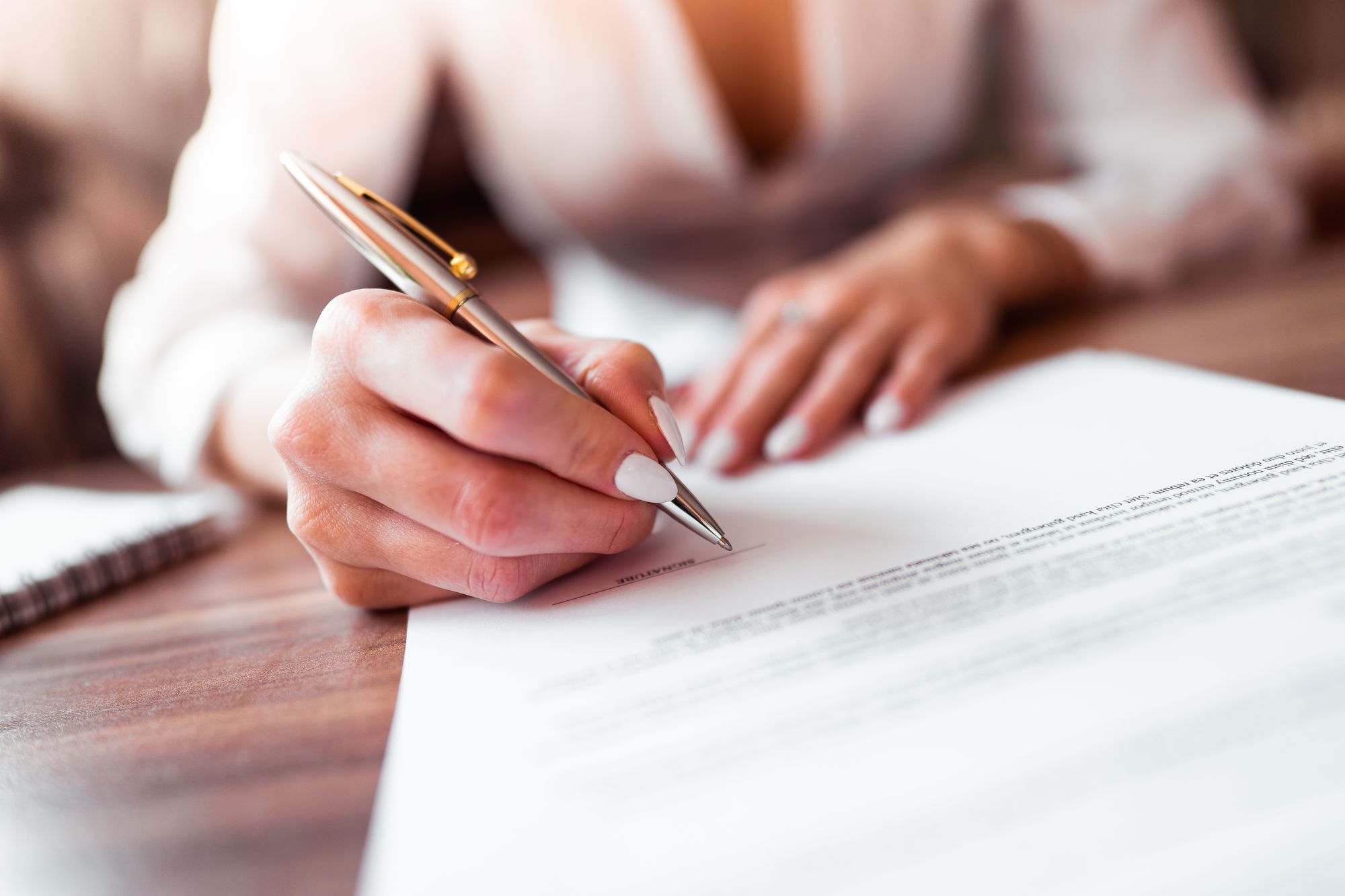 A picture of a woman signing an agreement
