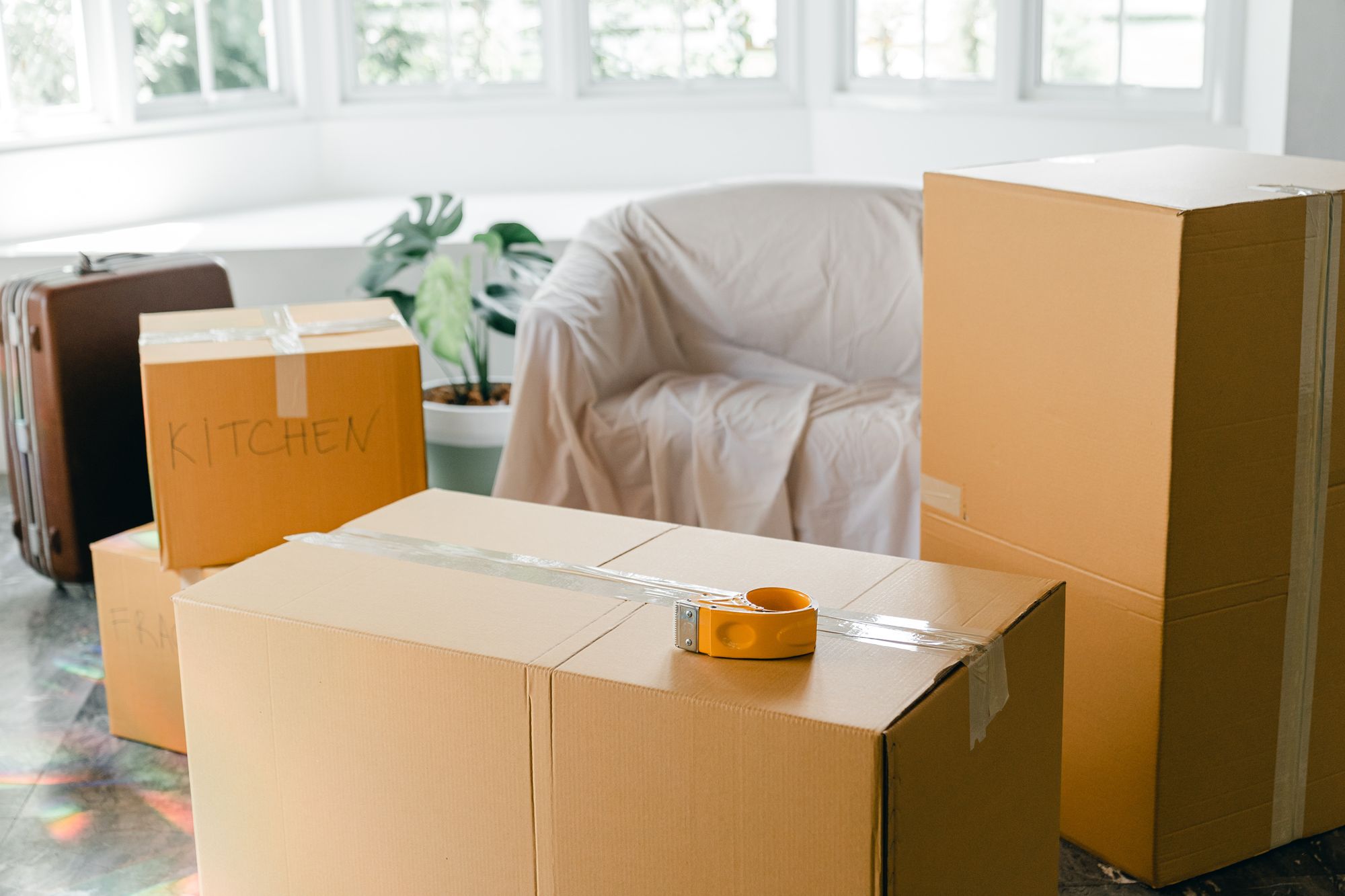 Photo of an empty apartment with packed moving boxes and a suitcase
