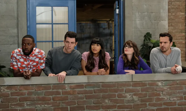 The cast of a TV series called "New Girl" stands outside on the balcony