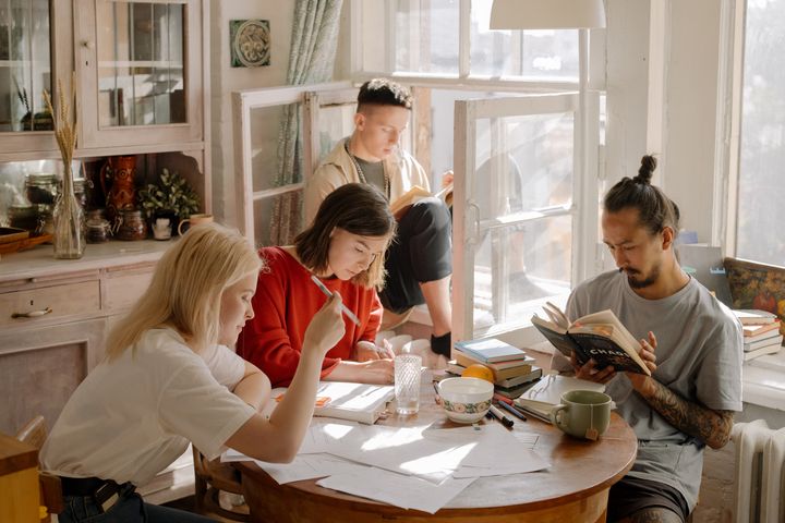 Photo of four roommates sitting at a table doing various activities