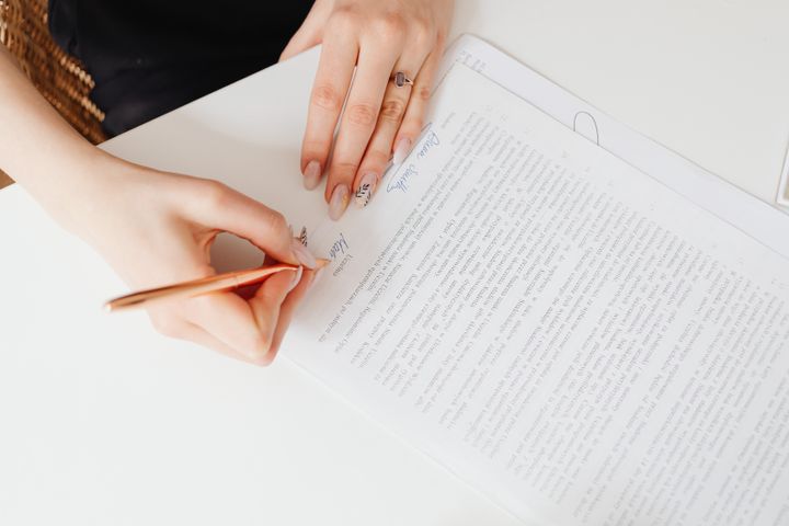 Photo of an individual signing their name at the bottom of a written agreement