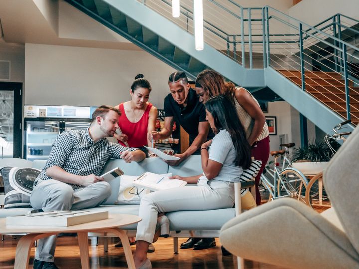 A group of people sitting on a couch and collaborating on a project in open space coworking area