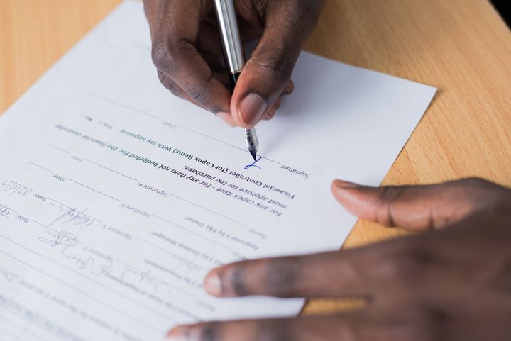 A person using a silver pen to sign a room rental agreement