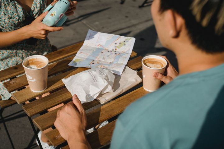 Two people drinking coffee, and looking at a map of a city