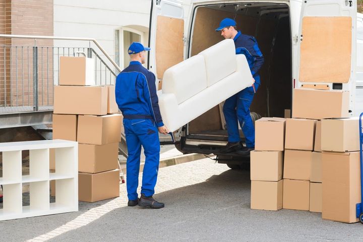 Movers carrying a small couch off a tr