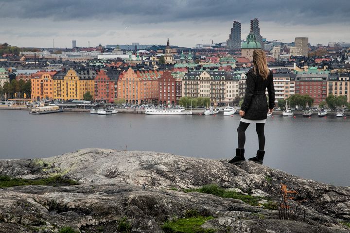 Photo of a woman standing atop a rock overlooking Södermalm in Stockholm, Sweden