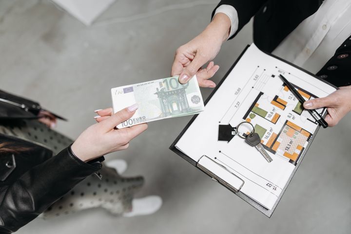 A woman handing payment to a landlord, in return for keys of the property