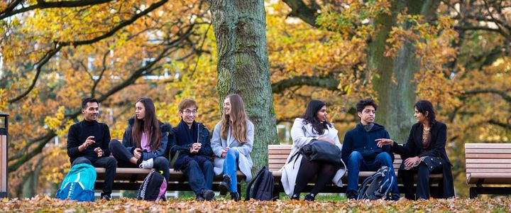 A group of students sitting on multiple benches on campus at the Aarhus University in Aarhus, Denmark