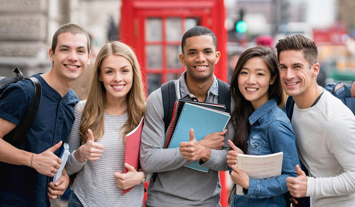 Group a students of different ethnicities holding college notebooks, smiling at the camera and giving a thumbs up