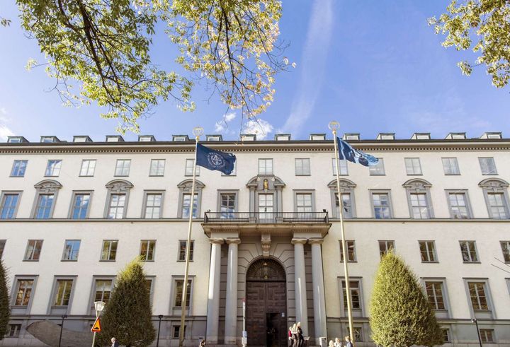 Frontal view of Stockholm School of Economics, showing flags waving at the entrance