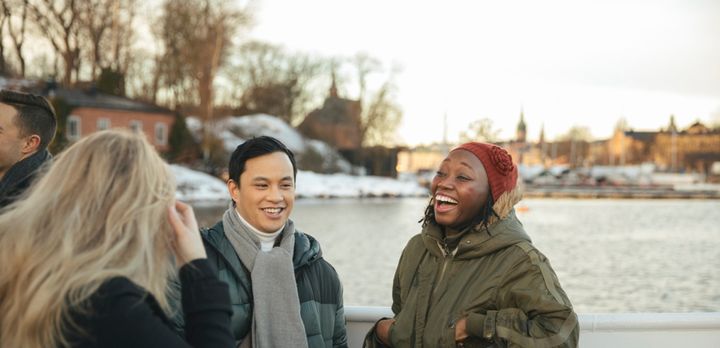 A group of three students talk and laugh