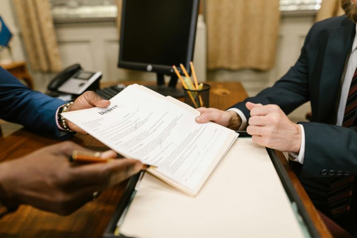 Close-up shot of a person holding up a paper for another individual to sign