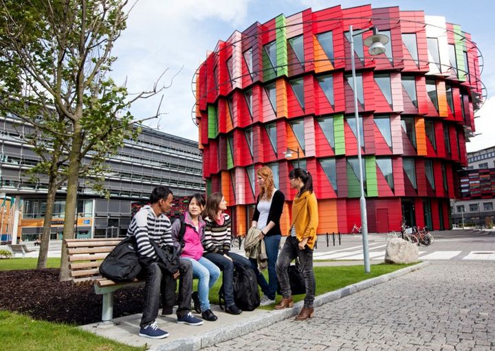 Students sitting in front of a colorful building at the University of Gothenburg in Sweden