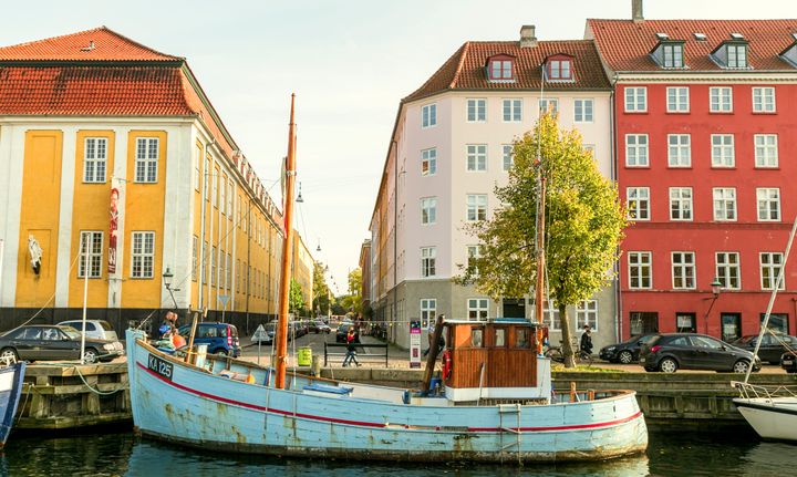 Photo of Nyhavn at Copenhagen, depicting a boat in front of three colorful buildings