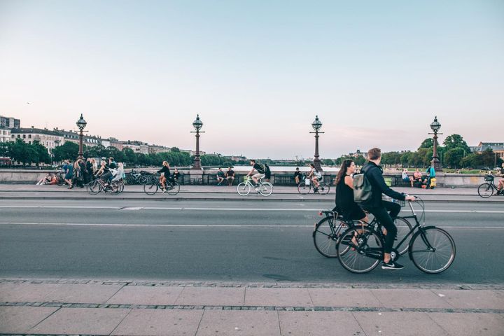 Multiple people riding their bikes on a street in Copenhagen, Denmark
