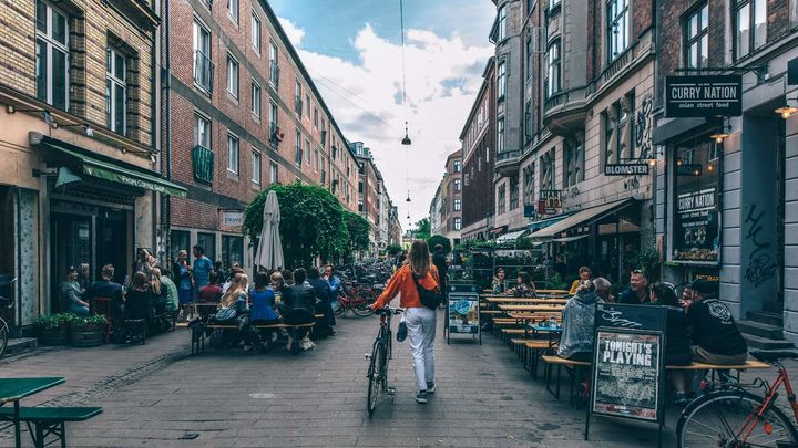 Woman walking her bike among the streets of Nørrebro
