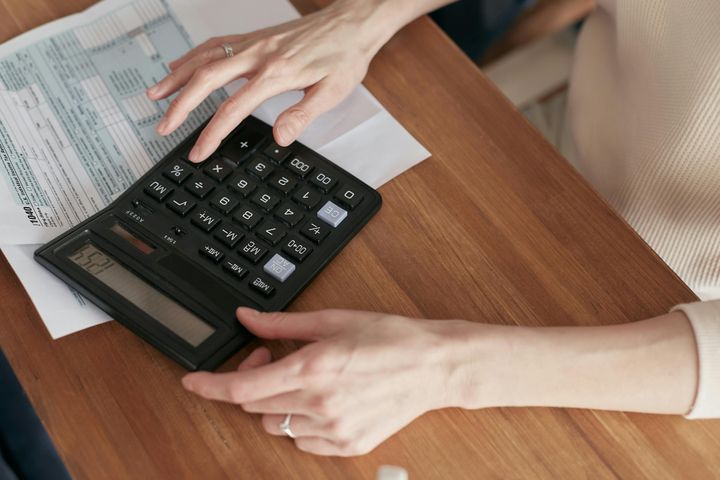 Woman holding calculator on top of pile of bills