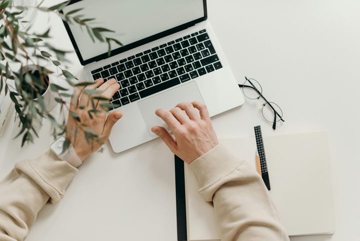 Woman typing on her laptop, with a coffee next to it