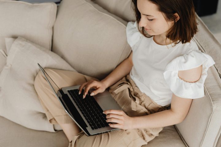 Woman typing on a laptop while sitting on a couch