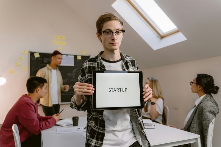 Man wearing eyeglasses, holding up a sign that says "Startup"